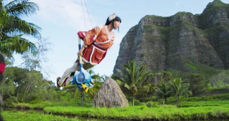 Ninja fighting woman in colorful costume as she slides back on wires and soars through air - steady cam shot