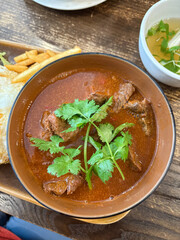 A bowl of beef stew with coriander on top.