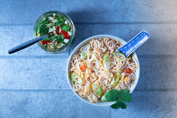 Bowl of noodles on gray floor background, top shot.
