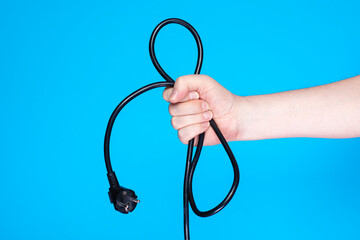 Electrical extension wire in hand against blue backdrop.
