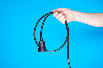 Household utility extension wire with socket and plug wrapped in a circle and held by a person&rsquo;s hand.