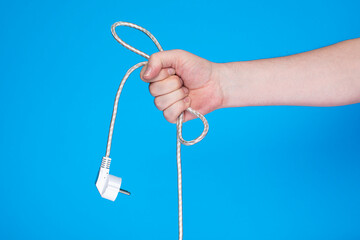 Hand holding white power cable on blue background.
