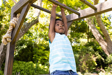 Fototapeta premium Child playing on monkey bars in backyard, enjoying sunny day outdoors