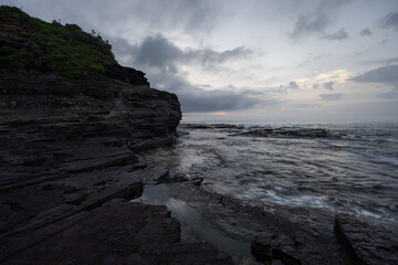 Cloudy sunrise view at rocky Austinmer Beach, Australia.