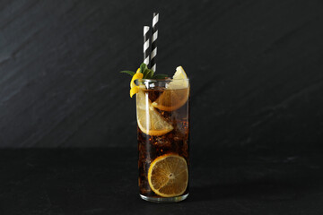 Fresh iced cola with lemon slices and mint on black table