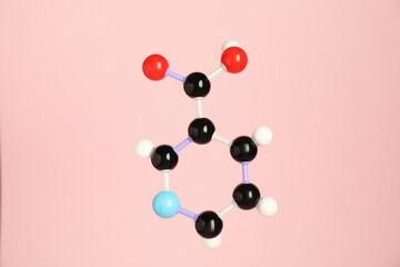 Molecule of niacin (vitamin B3) on pink background. Chemical model