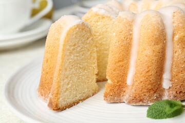 Delicious lemon cake with glaze and mint on light table, closeup