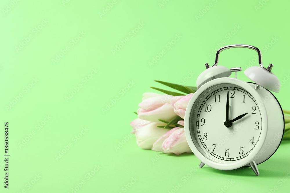 Poster spring time. alarm clock and beautiful tulips on green background, space for text