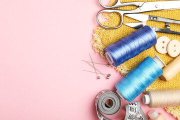 Different sewing supplies on pink background, flat lay. Space for text