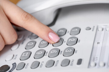 Woman dialing number on landline telephone, closeup