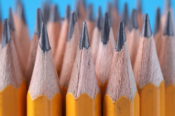Many pencils on light blue background, closeup