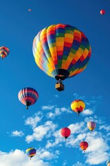 Obraz premium Vibrant balloons drift effortlessly through a bright azure sky, creating a stunning scene.