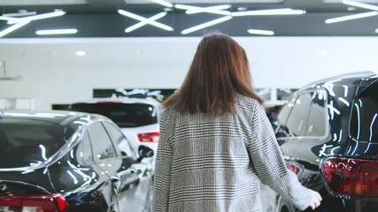 Woman in a stylish coat enters a luxury vehicle in an upscale car dealership during the afternoon