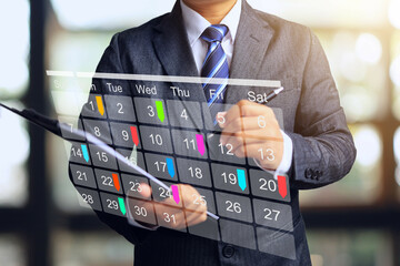 Businessman holding clipboard and making appointment or meeting plan on calendar.