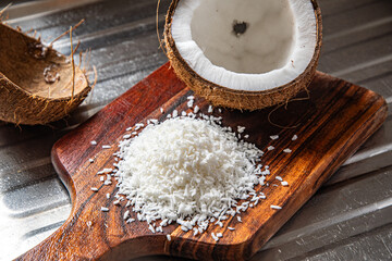 A split coconut lies on a wooden kitchen board, its fresh flesh sparkling in the light, and a coconut mug stands nearby as if inviting you to enjoy the tropical mood.