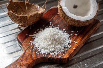 A split coconut lies on a wooden kitchen board, its fresh flesh sparkling in the light, and a coconut mug stands nearby as if inviting you to enjoy the tropical mood.