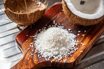 A split coconut lies on a wooden kitchen board, its fresh flesh sparkling in the light, and a coconut mug stands nearby as if inviting you to enjoy the tropical mood.