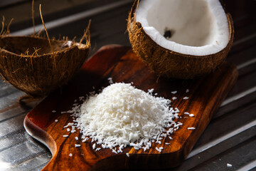 A split coconut lies on a wooden kitchen board, its fresh flesh sparkling in the light, and a coconut mug stands nearby as if inviting you to enjoy the tropical mood.
