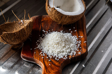 A split coconut lies on a wooden kitchen board, its fresh flesh sparkling in the light, and a coconut mug stands nearby as if inviting you to enjoy the tropical mood.