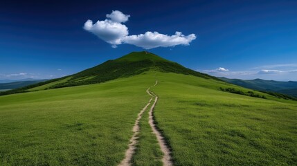 Lush green mountain path under a dramatic sky.  A winding trail ascends a verdant hilltop, leading to a peak.  Fluffy clouds drift serenely across a vibrant blue sky
