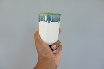 Hand holding a ceramic cup with a blue and white glaze finish
