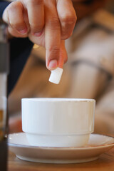 Sugar being added to a cup during a morning coffee break