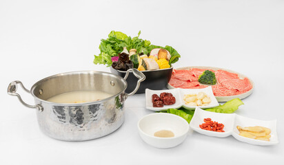 A mouthwatering selection of beef hot pot ingredients is beautifully arranged, featuring tender, thinly sliced beef ready to be cooked in a steaming, flavorful broth. The marbled beef glistens