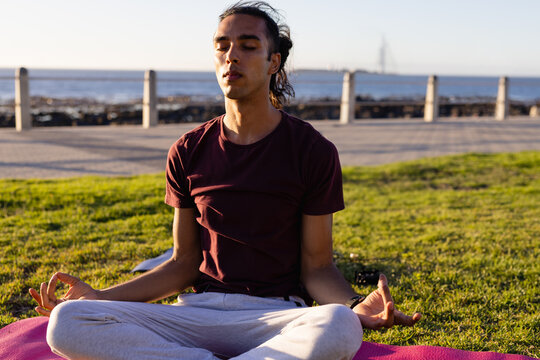Man meditating on yoga mat by seaside during sunset, finding inner peace