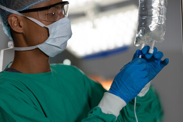 Medical professional adjusting IV drip in operating room, focused on patient care