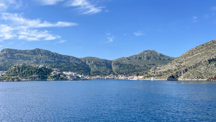 Coastal Village On A Greek Island Surrounded By Green Mountains And Clear Blue Sea, Scenic Landscape Under A Bright Sky, Summer Vacation Destination, Travel, Tourism, Mediterranean Lifestyle.