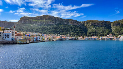 Fototapeta premium Colorful Waterfront Houses On Kastellorizo Island, Greece, Surrounded By Mountains And The Blue Sea, Idyllic Summer Destination, Traditional Architecture, Perfect For Travel, Tourism, And Cultural 