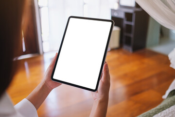 Mockup image of a woman holding tablet with blank desktop white screen on the bed at home
