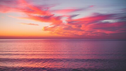 Obraz premium Stunning twilight view of a serene ocean, painted with vivid pink and orange clouds reflecting on the water's surface.