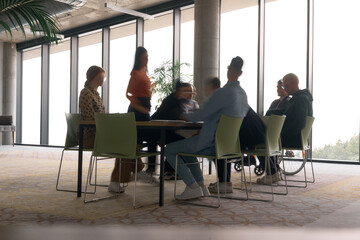 A diverse business team, working urgently around a conference table, collaborates on a meeting...