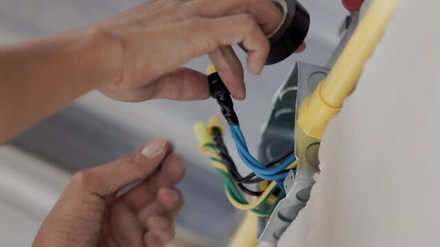 Electrician is wire wrapping by vinyl electrical tape.
