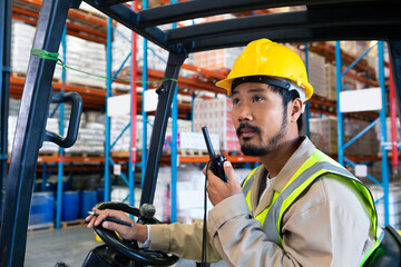 Warehouse worker in safety gear operating forklift and communicating via radio, copy space © wavebreak3