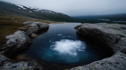 Mountaintop alpine pool in misty landscape