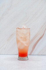 Colorful layered Peach cocktail in a tall glass with ice in a white background