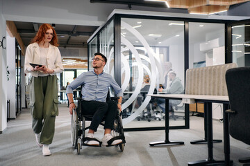 Business colleagues, collaborative business colleagues, including a person in a wheelchair, walk...