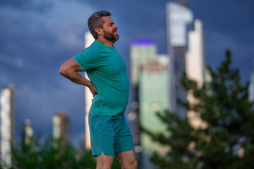 Pain in back after sport. Man with spine injury. Hurt while jogging outdoors. Muscle pain after...