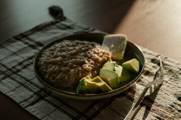 porridge with farmers soft white cheese and cut fresh avocado on wooden background, healthy eating for breakfast