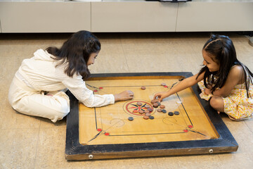 Indian girl kids playing carrom board game at home. Childhood holiday lifestyle and summer vacation. Playful children. Hobby and fun.