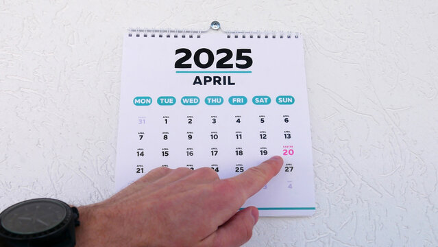 Close-up of a male hand pointing finger at Easter date 2025 on a wall calendar
