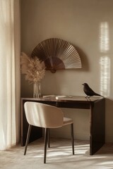 Modern minimalist workspace with warm tones and natural elements.  A decorative fan, pampas grass, and a dark bird add character to the serene setting