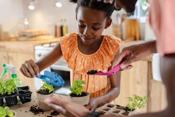 Young girl planting herbs with family at home, enjoying gardening together