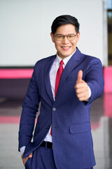 Smile asian face businessman trump up with navy blue formal suit for comfirm quality of product.