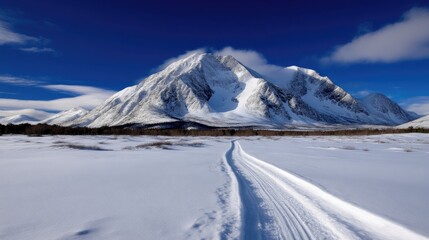 Obraz premium Snowy mountain path under a vibrant sky. A pristine winter landscape, featuring a well-worn ski track leading towards a majestic snow-capped mountain range
