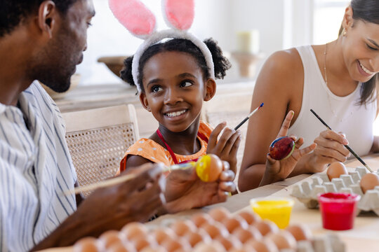 Family painting Easter eggs together at table, sharing joyful creative moments