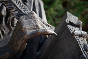 Bronze sculpture of hands holding a feather pen and writing on a paper