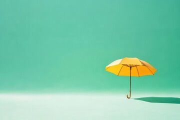 Yellow umbrella, teal background, studio shot, protection concept
